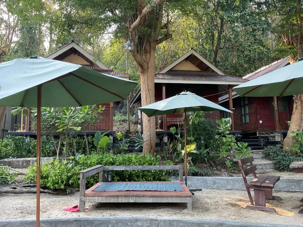 Wooden bungalows with garden seating and umbrellas at TipThong Hut
