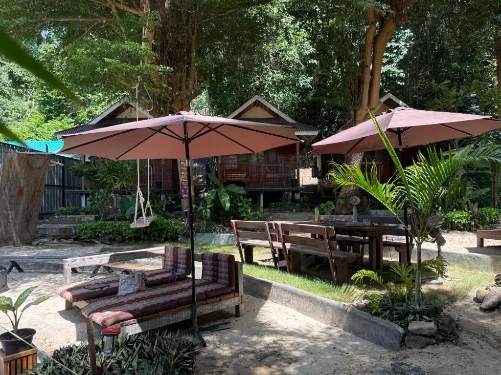 Salón de jardín con tumbonas y sombrillas frente a los bungalós de TipThong Hut