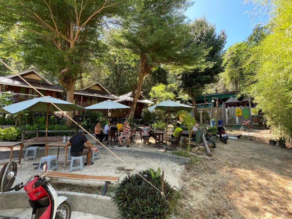 Terraza sombreada con mesas entre los bungalós de TipThong Hut
