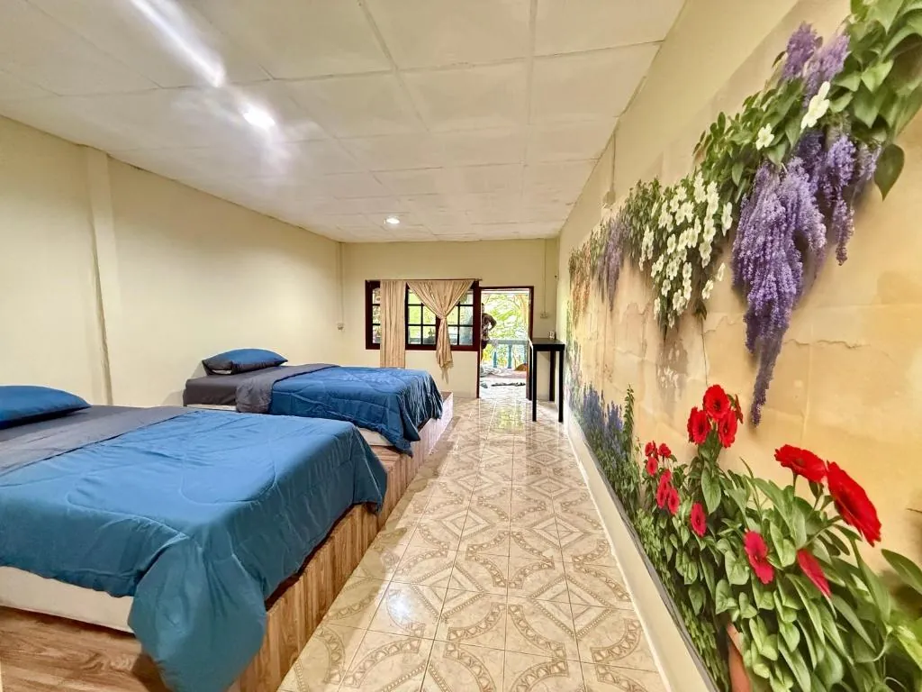 Habitación doble con dos camas individuales y mural floral en TipThong Hut